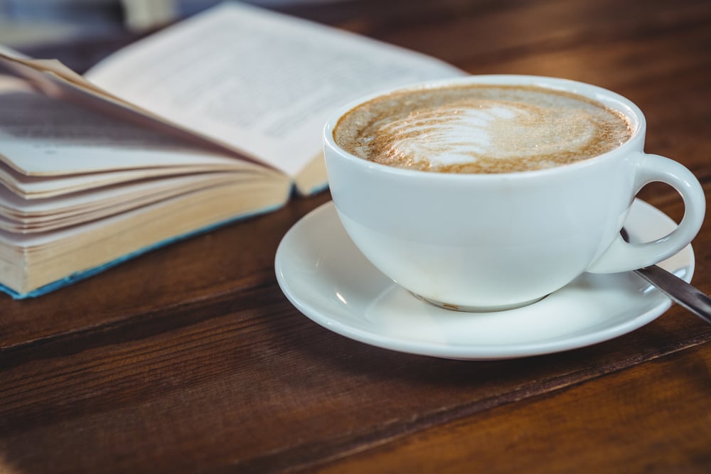 Close-up of cappuccino and book on table in cafeteria